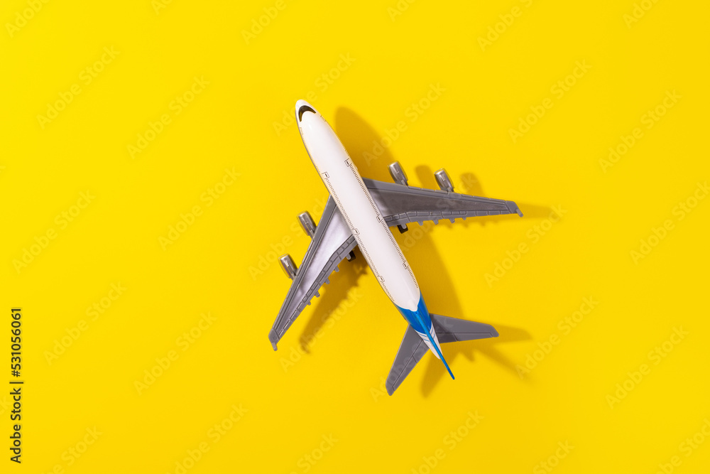 Top view of white model plane, airplane toy on isolated yellow background. Flat lay with copy space. Trip or travel banner. Top view of white model plane, airplane toy on isolated yellow background. Flat lay with copy space. Trip or travel banner.