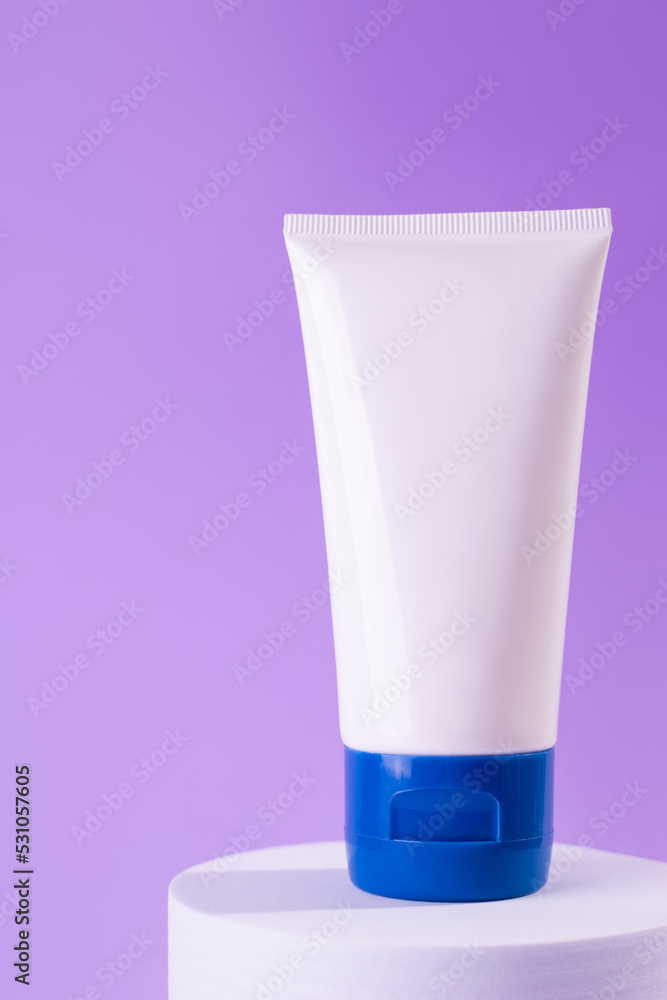 Feminine hygienic product tube on purple background on stand. Shampoo, hand cream, toothpaste white package side view. Skincare, facial creme, moisturizer container with copy space, mock up. Feminine hygienic product tube on purple background on stand. Shampoo, hand cream, toothpaste white package side view. Skincare, facial creme, moisturizer container with copy space, mock up.