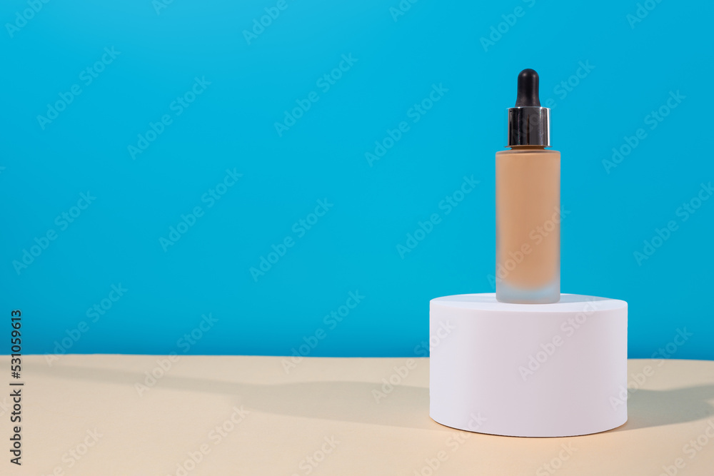 Bottle with foundation liquid beige cream on stand, white podium. Professional makeup product for perfect complexion. Woman accessories, base beauty product, primer, concealer. Bottle with foundation liquid beige cream on stand, white podium. Professional makeup product for perfect complexion. Woman accessories, base beauty product, primer, concealer.