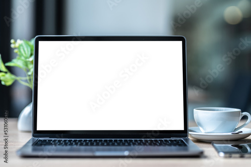 Mockup of laptop computer with empty screen with coffee cup and smartphone on table of the coffee shop background,White screen