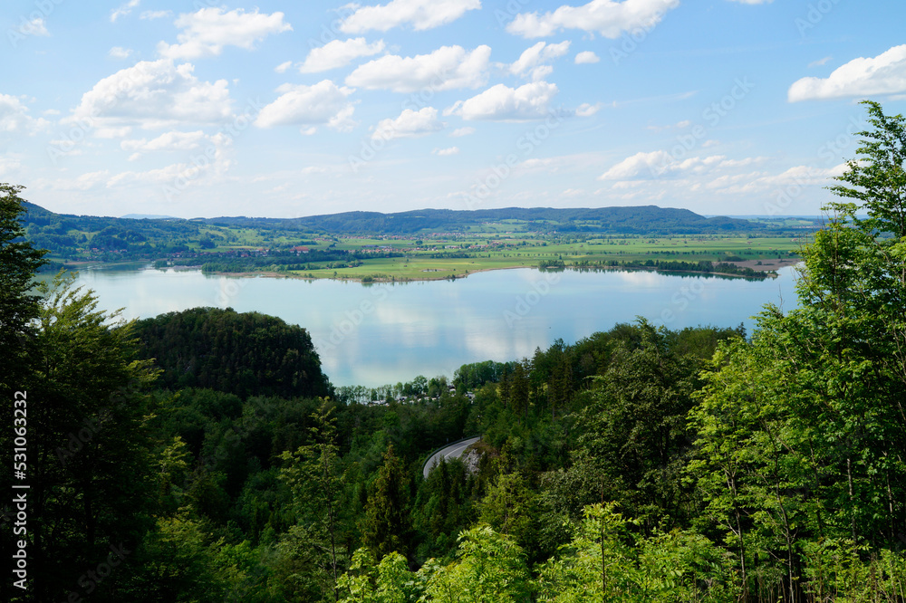 lake Kochel or Kochelsee in the scenic Bavarian Alps surrounded by the lush green trees on a sunny day in May (Bavaria, Germany)