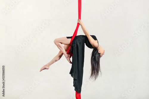 Flexible woman exercising on aerial silks