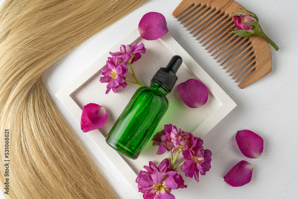 A green face serum or oil made of rose petals with flower extract lying between the petals, product marketing mockup. A concept of hair care in a salon or at home A green face serum or oil made of rose petals with flower extract lying between the petals, product marketing mockup. A concept of hair care in a salon or at home