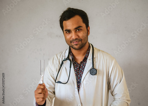 South asian doctor with a tuning fork in hand. Bangladeshi medical student with neurological diagnostic tool. photo