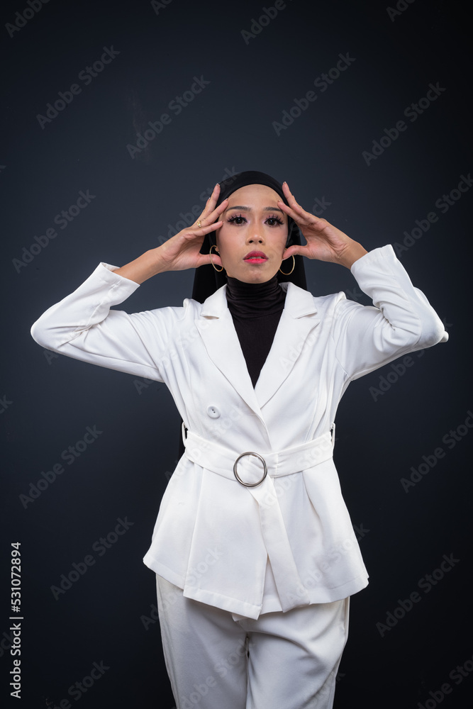 Portrait of a beautiful female model wearing hijab, a lifestyle apparel for Muslim women isolated on grey background. Idul Fitri and hijab fashion concept. Portrait of a beautiful female model wearing hijab, a lifestyle apparel for Muslim women isolated on grey background. Idul Fitri and hijab fashion concept.