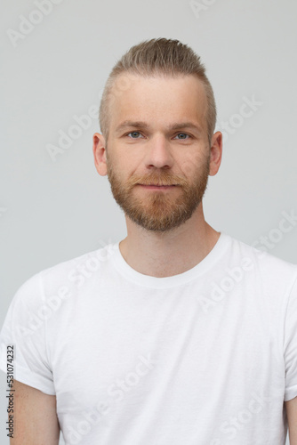 Portrait of handsome bearded man in white t-shirt isolated on gray background.