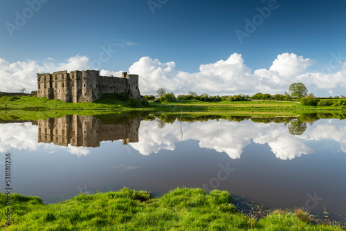 The magnificent ruins of Carew Castle reflected in the Mill Pond in spring, Carew, Pembrokeshire, Wales photo