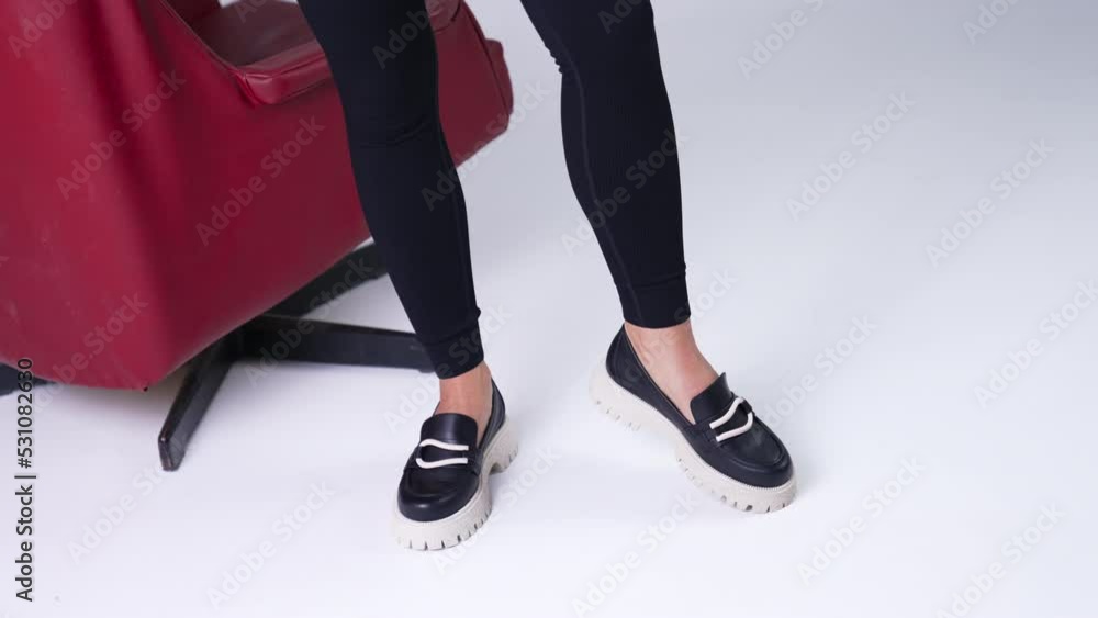 Modern black shoes on white tractor soles performing. Model in black pants demonstrates fashionable stylish shoes. Close up. Modern black shoes on white tractor soles performing. Model in black pants demonstrates fashionable stylish shoes. Close up.