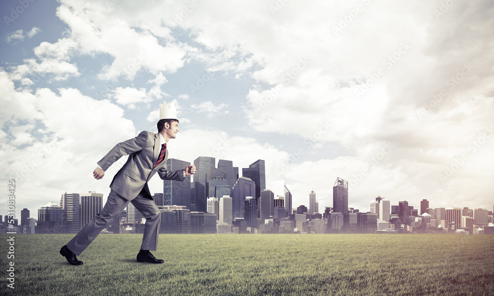 King businessman in elegant suit running on green grass and modern cityscape at background King businessman in elegant suit running on green grass and modern cityscape at background