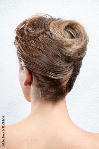 Back view of young woman. Portrait of a nude young white blonde woman. Blond styled hair. Stylish hairstyle. Isolated on a light