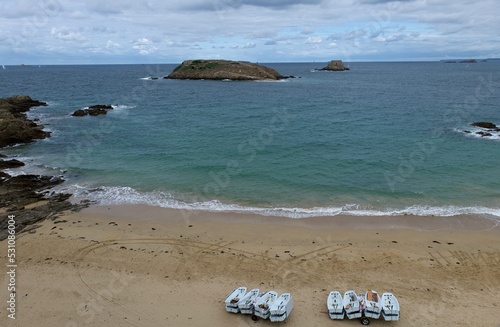 playa del oceano atlantico en marea alta con islas al fondo yen la arena se observan seis pequeñas embarcaciones photo