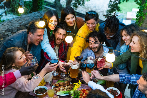 Foto Happy friends having fun drinking at house dinner pic nic bbq party - Mixed age