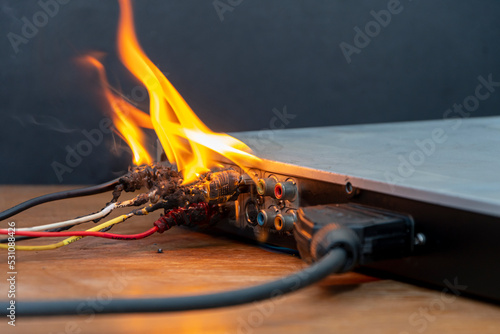 фотографія A DVD player is burning on the table, network cables are burning and sparking, flames are rising up, a fire has started in the apartment