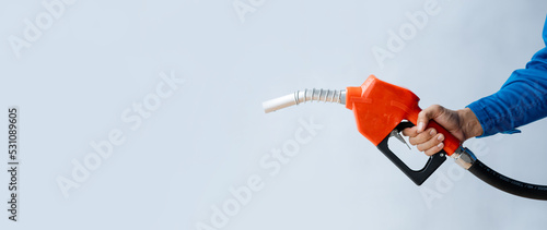 Person holding a gas nozzle on a white background, fuel consumption, petrol-fueled cars, fluctuating oil prices, using alternative fuels for driving.