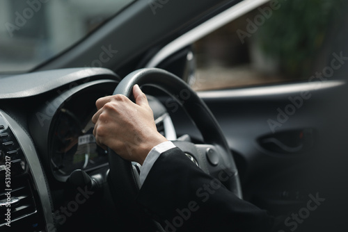 A man in a suit is driving a car to work  he is driving a car to work at the company. Vehicle driving concept.