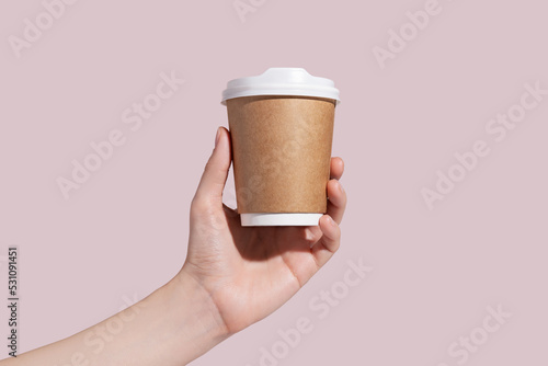 Fényképezés Mockup of woman hand holding up a Coffee paper cup on pink background