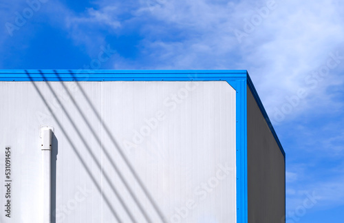 Air conditioning pipeline on white wall of office container against cloud on blue sky background