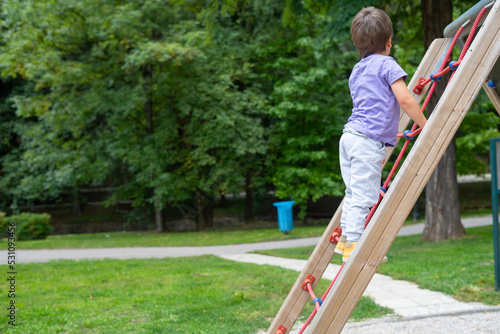 A boy (child) (not recognizable) climbs a rope ladder in a children's park playground