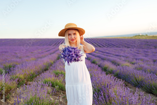 Attractive young woman in summer dress standing among the lavender fields