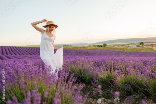 Attractive young woman in summer dress standing among the lavender fields