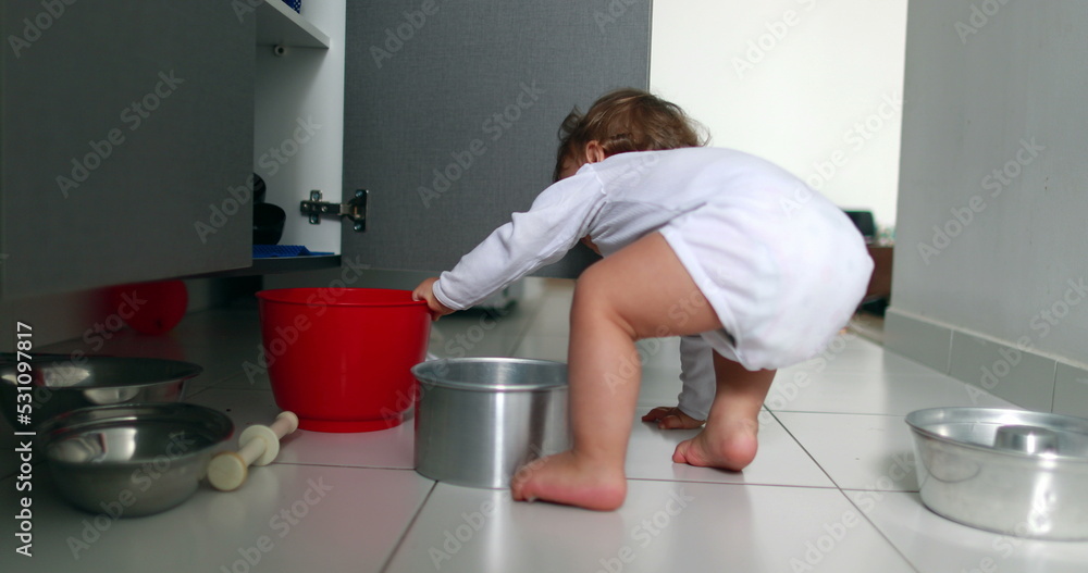 Baby getting up from the kitchen floor. Baby playing with kitchen utilities, opening closet. Toddler at play with pots and pans Baby getting up from the kitchen floor. Baby playing with kitchen utilities, opening closet. Toddler at play with pots and pans