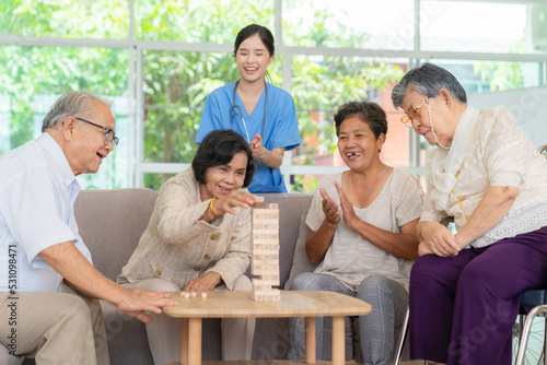 Dementia therapy in playful way. Group of senior elder people stay at nursing home, enjoy activity.relation playing Jenga or tumbling tower wood block game. Training fingers and fine skills