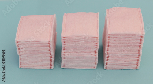 Almoadillas de algodon en color rosa sobre fondo azul, usadas para el cuidado facial.  photo