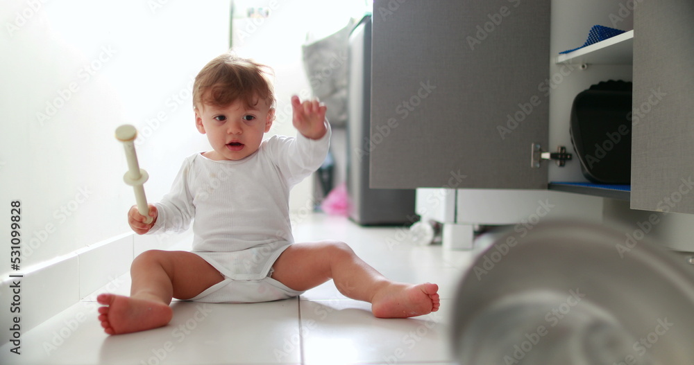 Baby boy hitting metal kitchen utensil on floor. One year old toddler drumming pans and pots Baby boy hitting metal kitchen utensil on floor. One year old toddler drumming pans and pots