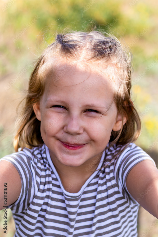 Smiling little girl in the park. Copy space. Happy child looking at the camera. Portrait of a laughing kid outside. Take a selfie