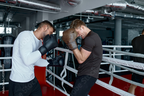 Foto Two sparring partners in boxing gloves practice kicks