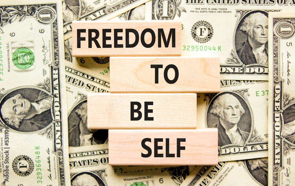 Freedom to be self symbol. Concept words Freedom to be self on wooden blocks on a beautiful background from dollar bills. Business, psychological freedom to be self concept.
