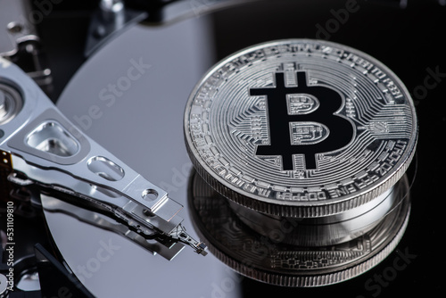 Silver Bitcoin coin on the opened HDD disk. Electronic money, cryptocurrency