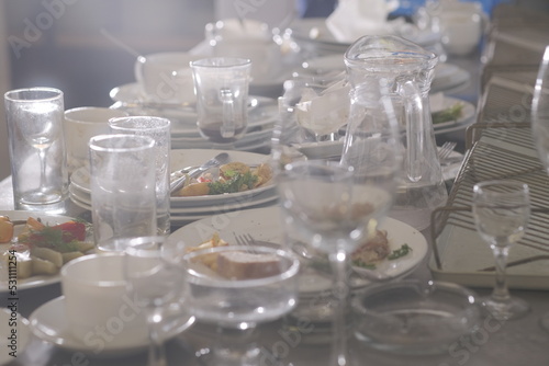 Dirty plates and glasses after a meal in the kitchen in the restaurant. Heap or pile of unclean glass and plates of breakfast or lunch table.