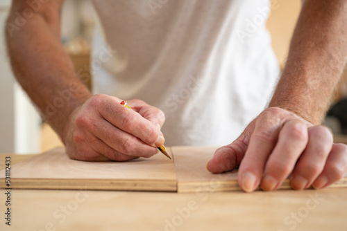 Close up of carpenter hands working on wood craft at workshop to produce construction material or wooden furniture. Professional tools for crafting. DIY work concept.