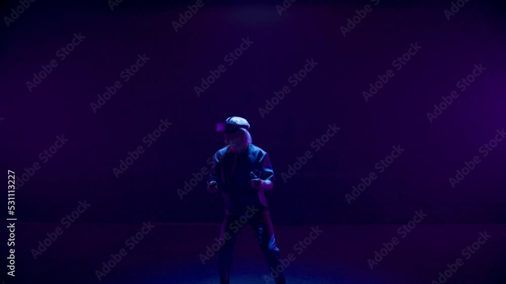 Vr man gesturing game in neon lights room. Blonde player use headset controllers Vr man gesturing game in neon lights room. Blonde player use headset controllers