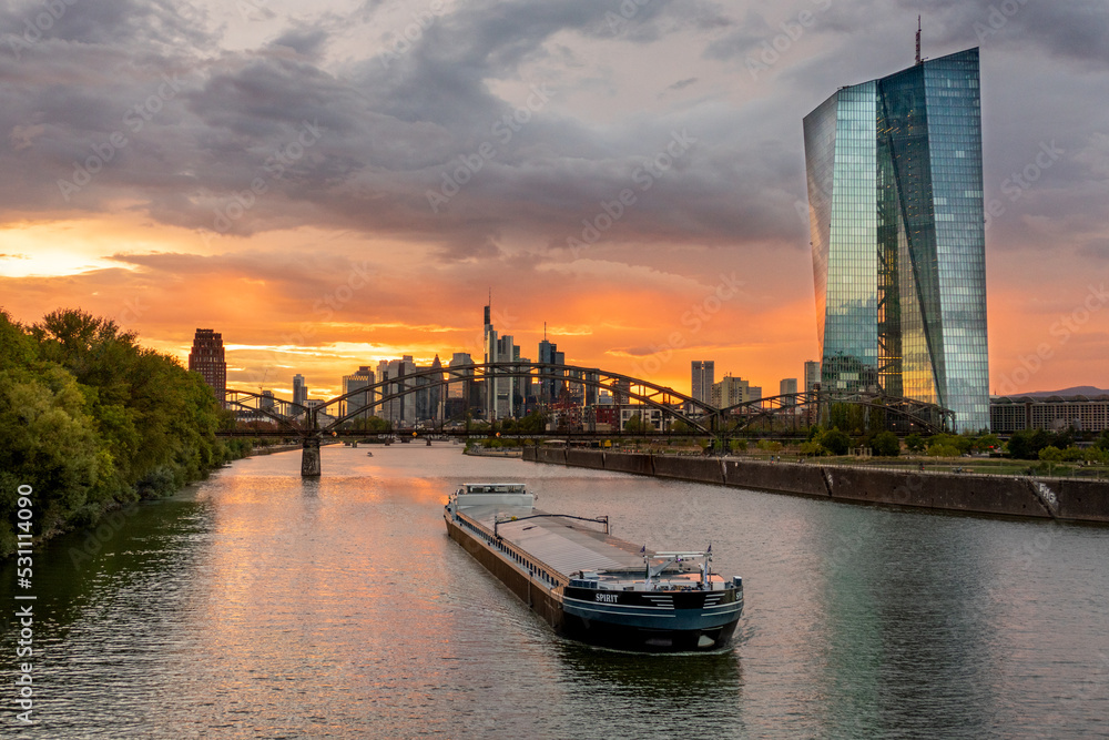 Naklejka premium Europäische Zentralbank (EZB) beim Sonnenuntergang mit dunklem Himmel mi Frankfurts Skyline im Hintergrund 