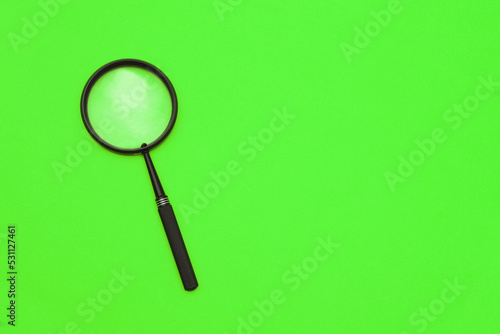 Loupe or magnifying glass on a green background. Shallow depth of field
