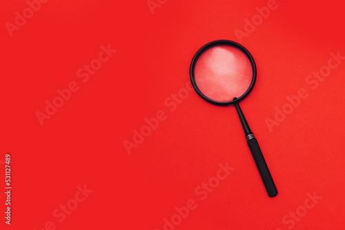 Loupe or magnifying glass on a red background. Shallow depth of field