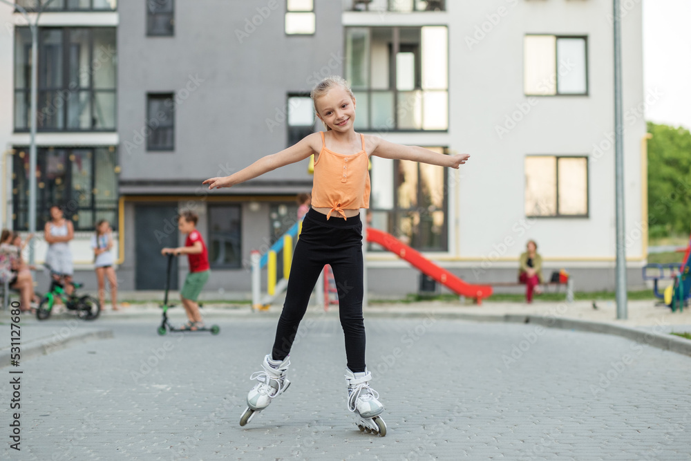 Pretty child on roller skates riding. Little girl learning to roller skate outdoors in playground. Pretty child on roller skates riding. Little girl learning to roller skate outdoors in playground.