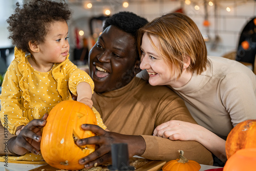 Fotografie Multi-ethnic family with small child carving a pumpkin preparing it for Hallowee