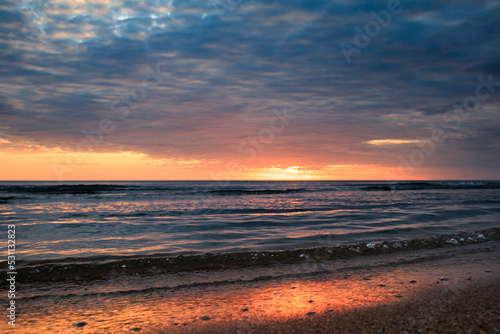 Coast of the Caspian Sea at sunset  pink-orange clouds  water  beach.