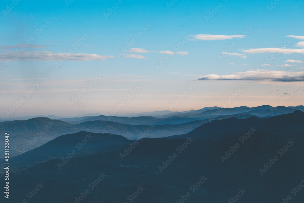 clouds over the mountains at sunrise with blue sky and clouds