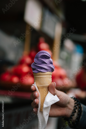 Purple lilac berry savor very tasty ice cream. Girl's hand holds in a waffle cup in a napkin. Food for pleasure and enjoy