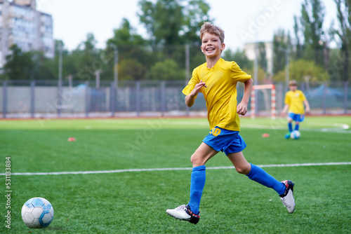 Football soccer training for kids. Smiling boy attending soccer training on school field. Soccer practice for children. physical education class. Sport happy concept;
