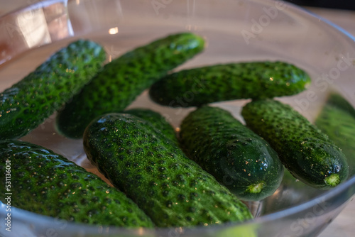 handmade marinated or pickled cucumbers with dill  garlic  and spices in a bowl and jar  rustic wooden table  homemade pickles  canning for the winter 