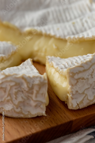 Camembert Cheese pieces close-up on a wooden cut board