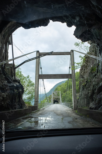 Kyrping, Norway - June 9, 2022: the old Akra Fjord road, POV from a Tesla Model 3 driving on the scenic route. Tunnel and bridges in a cloudy spring day. Selective focus photo