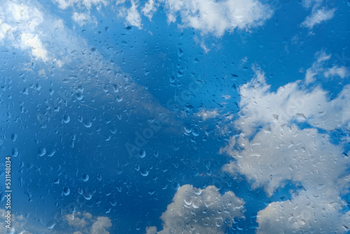beautiful cloudscape in window, blue texture of glass background with water drops, place for text, horizontal banner with blurry bokeh, nature protection, Severe Weather