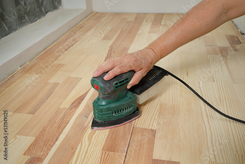 Bilde på lerret Closeup of worker hand sanding wooden floor or stairs using  power tool