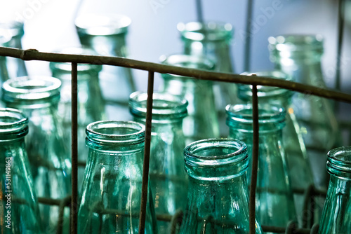 Metal crate of glass antique milk bottles on steps of house. Delivery of dairy products, milkman